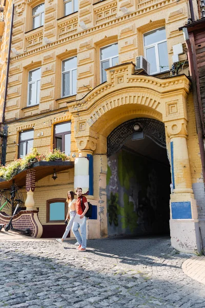 Haritalı ve dürbünlü gezginler şehir caddesindeki binanın yakınında yürüyorlar. 