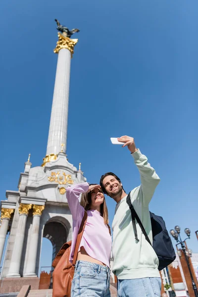 KYIV, UKRAINE - 1 Eylül 2021: Bağımsızlık Meydanı 'nda cep telefonundan selfie çeken pozitif turistler 