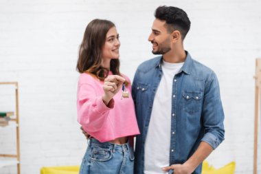 Blurred multiethnic couple holding key in living room 