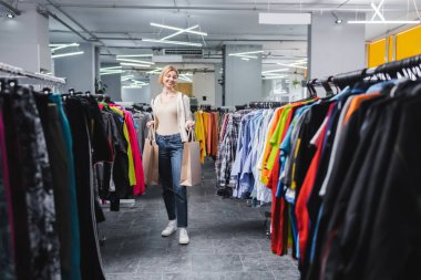 Positive blonde woman holding shopping bags in vintage store 