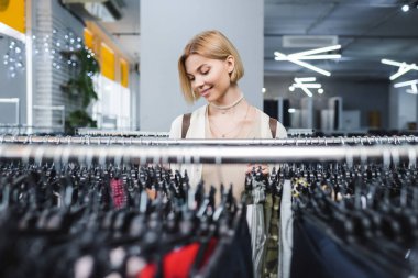 Positive woman choosing clothes in retro store 