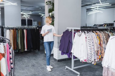 Blonde retailer holding digital tablet in second hand 