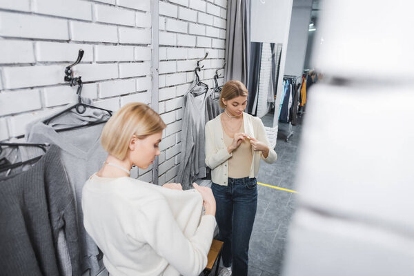 High angle view of woman looking at jumper near mirror in second hand 