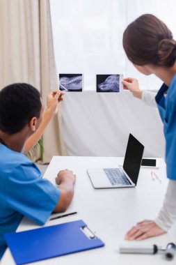 Klinikteki cihazların yakınındaki ultrason taramalarına bakan çok ırklı, bulanık veterinerler. 
