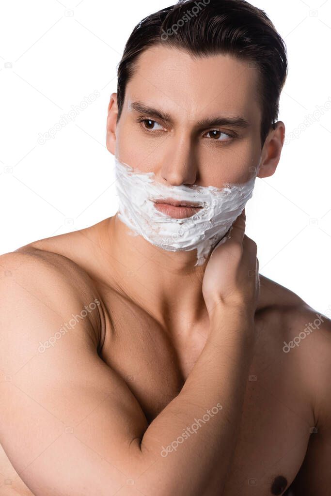 man with naked shoulders and shaving foam on face looking away isolated on white