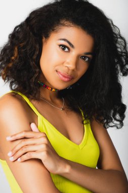 Sarı bluzlu Afro-Amerikan kadının portresi. Gri üzerinde yalnız poz veriyor. 