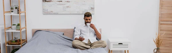 Joven Afroamericano Hombre Sosteniendo Taza Café Uso Teléfono Inteligente Mientras —  Fotos de Stock