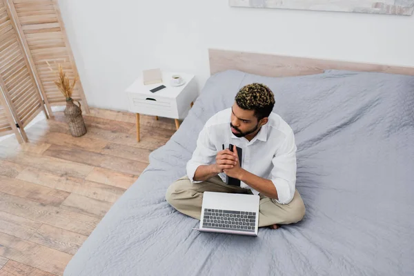 Yatağında Dizüstü Bilgisayarla Oturan Boyalı Saçlı Dalgın Afro Amerikan Adamın — Stok fotoğraf