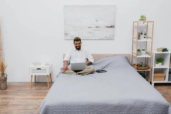 Fröhlicher Afrikanisch Amerikanischer Mann Drahtlosen Kopfhörern Mit Laptop Bett — Stockfoto