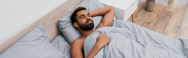 high angle view of young african american man sleeping in bed, banner