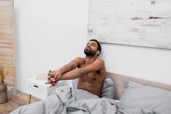 Hombre Afroamericano Sin Camisa Con Las Manos Apretadas Estirándose Cama — Foto de Stock