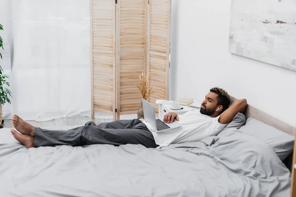 Hombre Afroamericano Auriculares Inalámbricos Viendo Película Mientras Está Acostado Cama — Foto de Stock