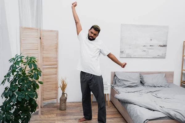 Bebaarde Afro Amerikaanse Man Stretching Buurt Vouwen Scherm Moderne Slaapkamer — Stockfoto