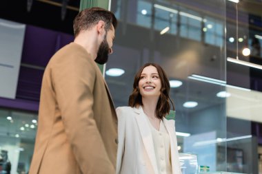 Low angle view of smiling young woman looking at boyfriend in jewelry shop 