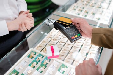Kuyumcuda hediye ve satıcının yanında kredi kartıyla ödeme yapan müşterinin kırpılmış görüntüsü 