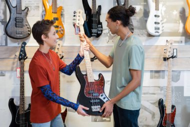 KYIV, UKRAINE - 16 Şubat 2022: Müzik dükkanında satıcının yanında elektro gitar tutan mutlu Afrikalı Amerikalı müşteri 