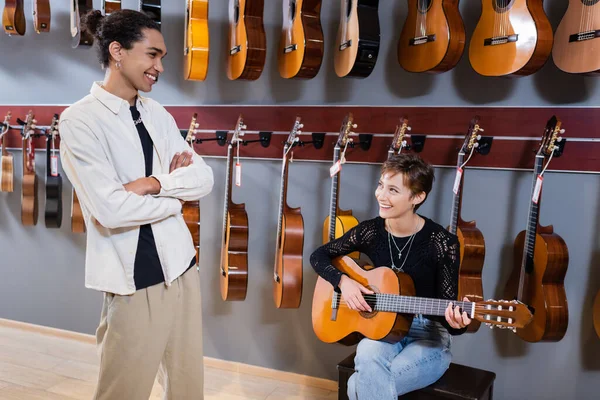 Mujer Sonriente Tocando Guitarra Acústica Cerca Vendedor Afroamericano Tienda Música — Foto de Stock