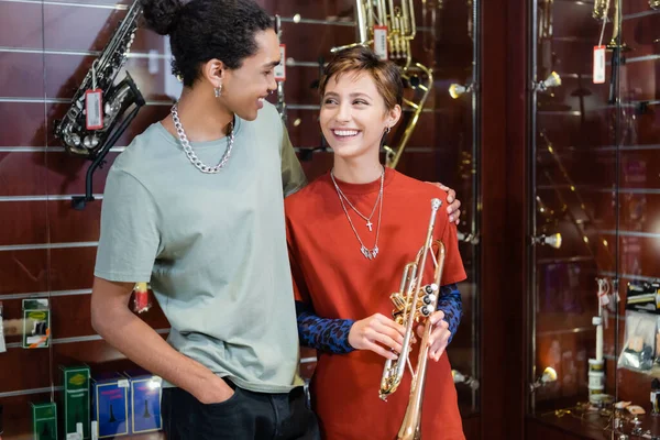 Mujer Alegre Sosteniendo Trompeta Mirando Novio Afroamericano Tienda Música —  Fotos de Stock