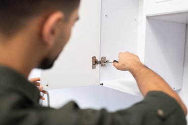 Blurred man fixing kitchen cabinet at home 