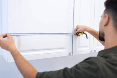 Blurred muslim man measuring kitchen cabinet at home 