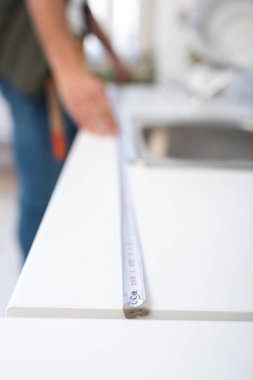 Cropped view of blurred craftsman measuring kitchen worktop 
