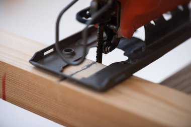 Close up view of jigsaw machine and wooden plank at home 