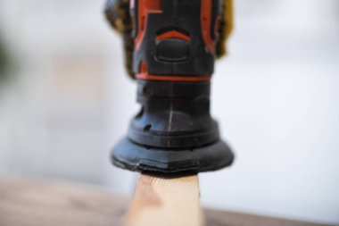 Close up view of blurred electric sander on wooden board at home  clipart