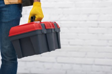 Cropped view of man in glove holding tool box at home 
