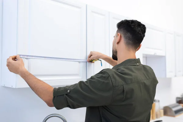 Young Muslim Man Measuring Kitchen Cabinet Home — Foto de Stock