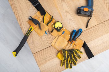 Top view of tools in belt near electric screwdriver on table 