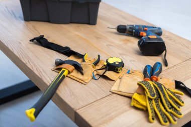 Tools in belt near blurred box and electric screwdriver on table 