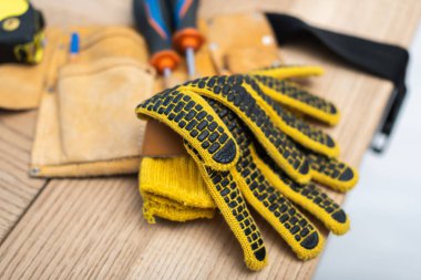 Close up view of gloves near blurred tool belt on table 