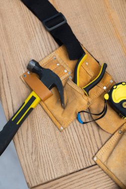 Top view of hammer and tools in belt on table 