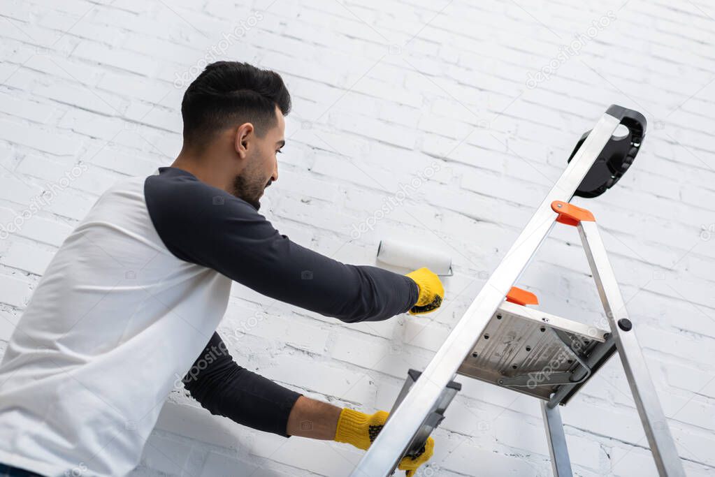 Low angle view of muslim man dying brick wall in living room 