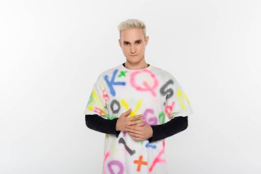 young gay in t-shirt with alphabet print looking at camera isolated on grey