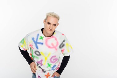 blonde gay man in stylish t-shirt looking at camera isolated on grey