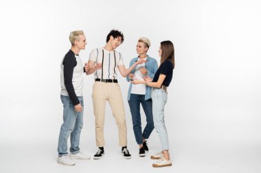 cheerful young man talking and gesturing near young friends on grey background