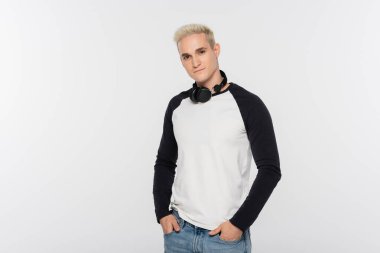 trendy man in black and white long sleeve shirt posing with hands in pockets isolated on grey