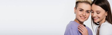 young lesbian couple with makeup smiling isolated on grey, banner