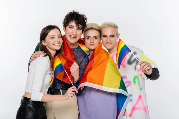 smiling people of diverse identity holding lgbtq flags and looking at camera isolated on grey