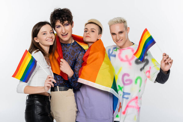 smiling lgbtq community people with rainbow flags looking at camera isolated on grey