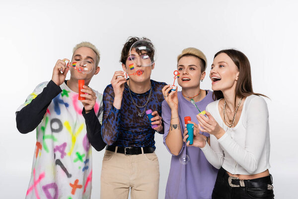 joyful lgbtq community friends having fun and blowing soap bubbles isolated on grey