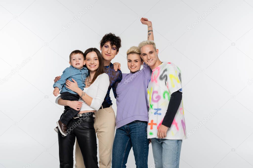 happy lesbian woman holding toddler boy near lgbtq community friends isolated on grey