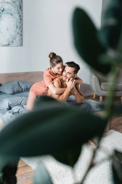 Genç baştan çıkarıcı kadın yatak odasında gülümseyen adama sarılıyor.