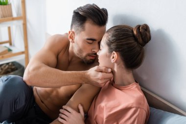 Yatak odasında kız arkadaşının yüzüne dokunan, gözleri kapalı seksi kaslı adam.