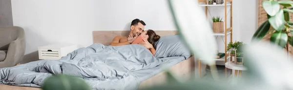 前景はぼやけたベッドの上で陽気な男の抱擁のガールフレンド バナー — ストック写真