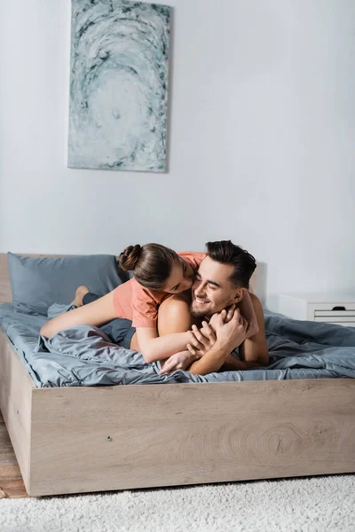 Sensual Woman Hugging Kissing Smiling Boyfriend Lying Grey Bedding — Stock Photo, Image