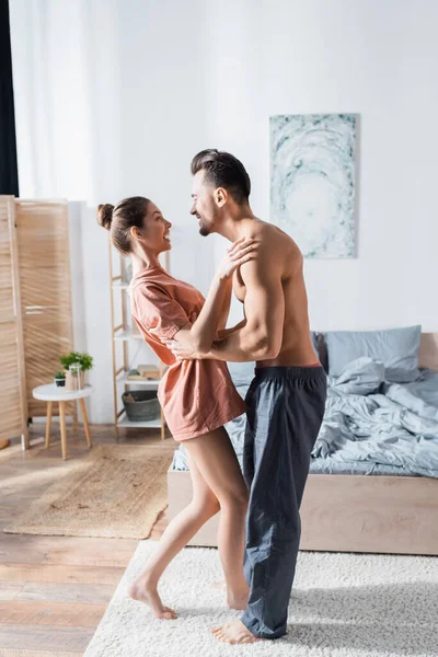 快乐的年轻夫妇在卧室里笑着跳舞的侧视图 — 图库照片