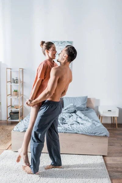 Side View Muscular Shirular Man Raising Amazed Girlfriend Bedroom — стоковое фото