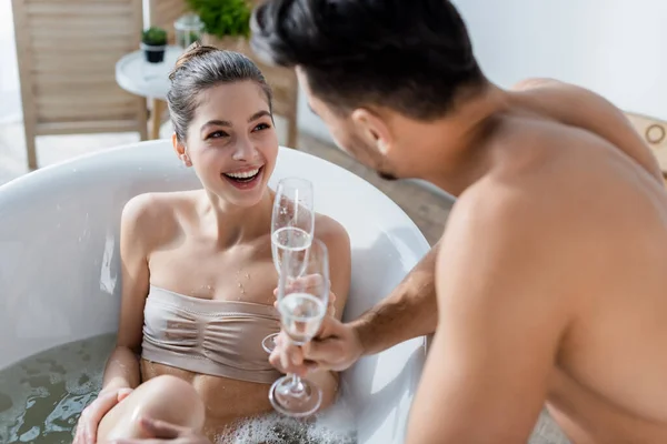 快乐的女人洗澡 看着香槟酒杯旁边模糊的男朋友 — 图库照片